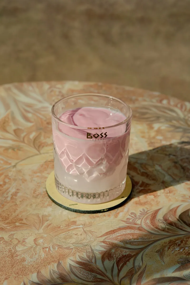 A pink cooler in a cut BOSS tumbler on a marble counter.