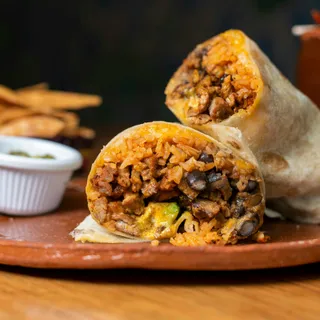 A burrito on a board beside rustic potato wedges.