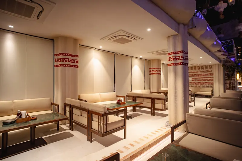 A quiet corner of the mezzanine lounge in warm light, sofas and low tables against a patterned column.