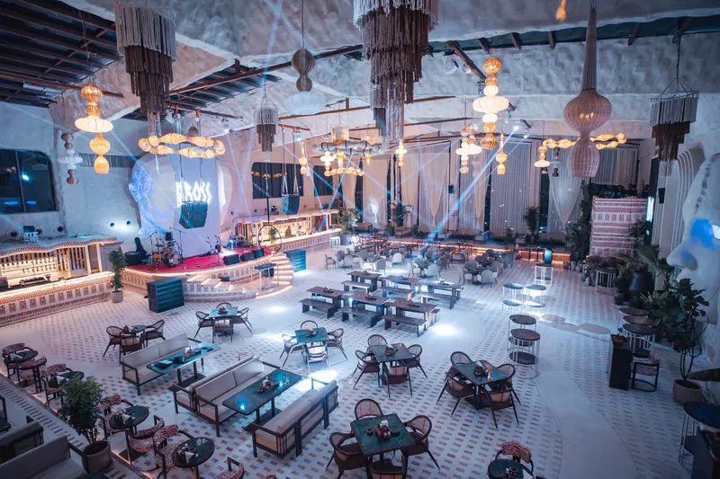 The bar counter at night, the BOSS sign glowing on the wall and blue beams reaching across the open floor.